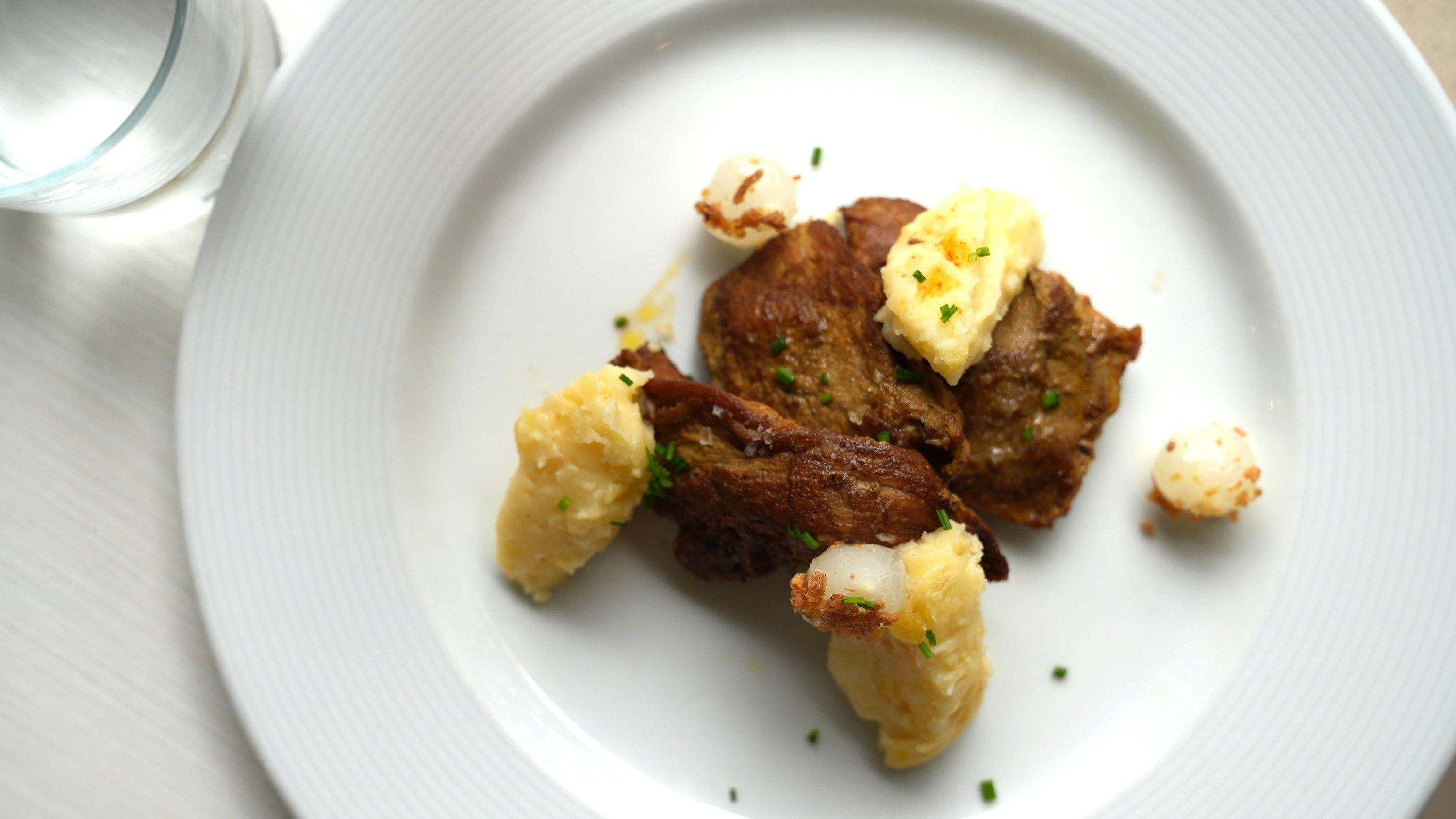 a white plate topped with meat and mashed potatoes