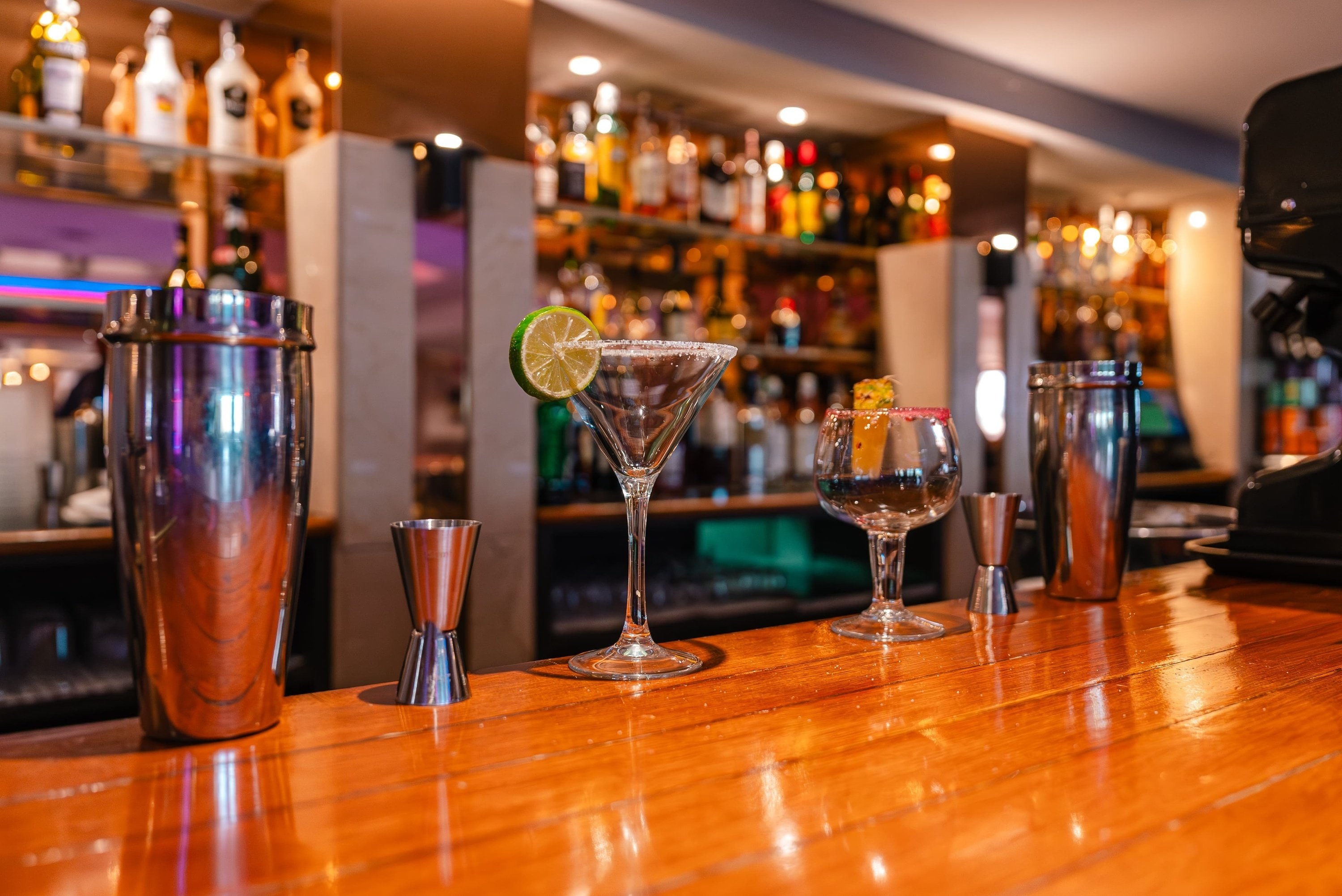 tres cócteles están sobre un mostrador de madera en un bar