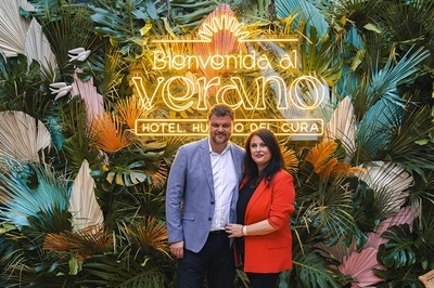 a man and woman standing in front of a sign that says bienvenido al verano - 