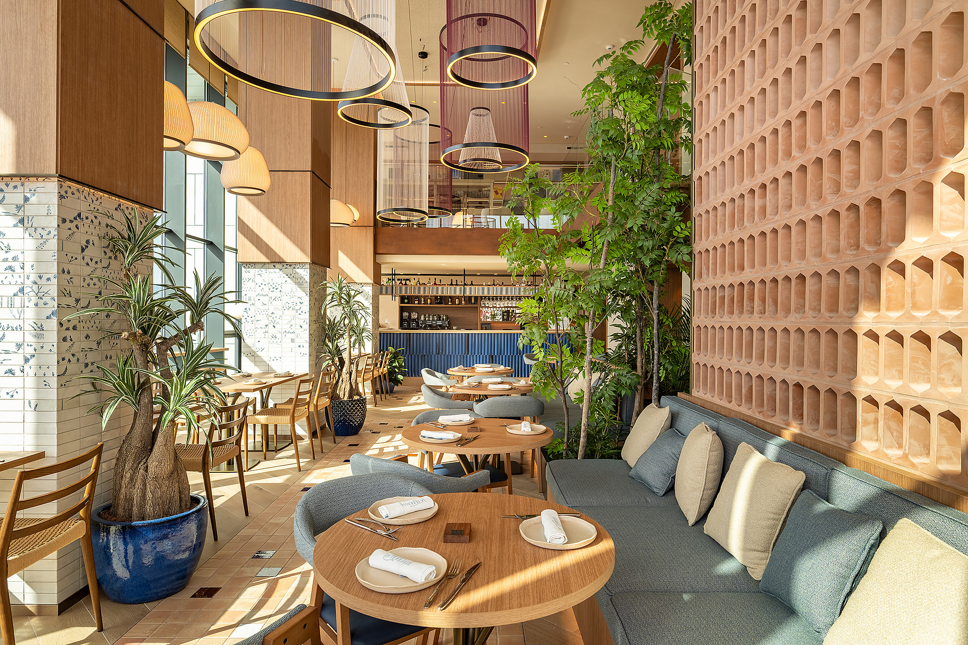Comedor interior de hotel con mesas de madera, plantas y sofás cómodos, creando un ambiente moderno y acogedor. Port Benidorm Hotel & Spa | Alicante | Port Hotels | Web oficial
