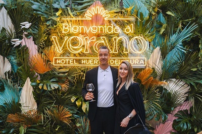 a man and woman standing in front of a sign that says bienvenido al verano - 