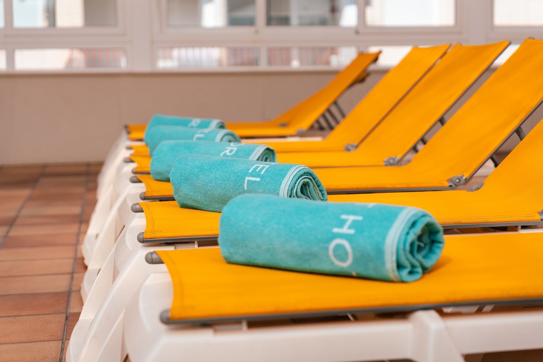 a row of yellow lounge chairs with towels on them that say relax