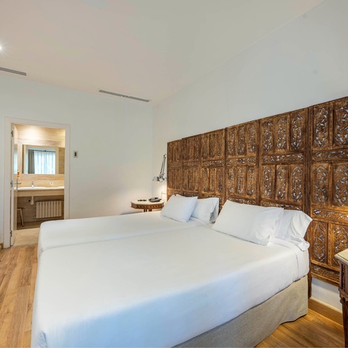 a bedroom with two beds and a wooden headboard