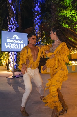a man and woman are dancing in front of a sign that says bienvenido al verano - 