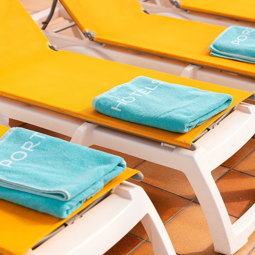 a yellow lounge chair with a blue towel that says port on it