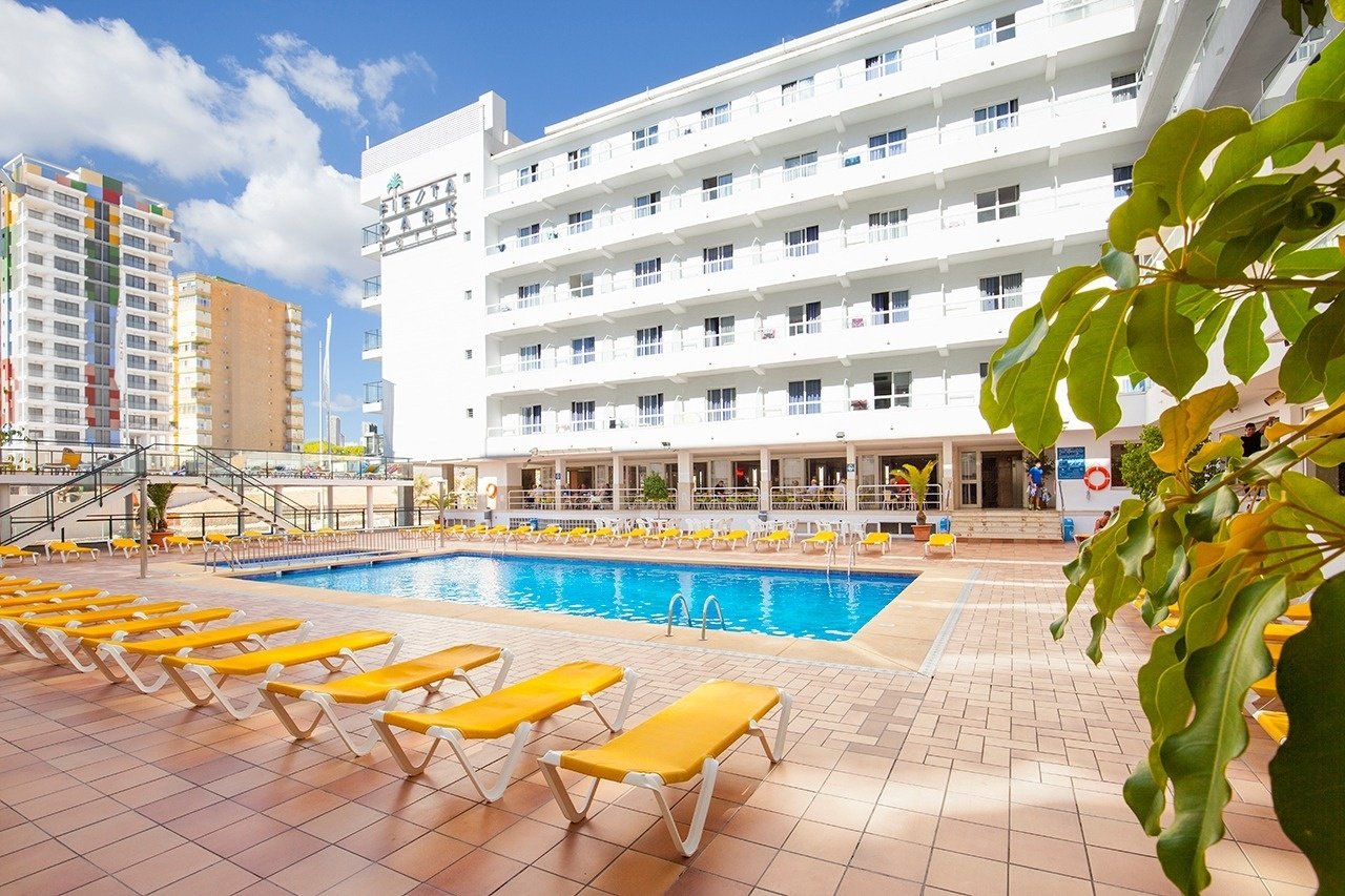 a large swimming pool surrounded by chairs and a building that says ' hotel ' on it