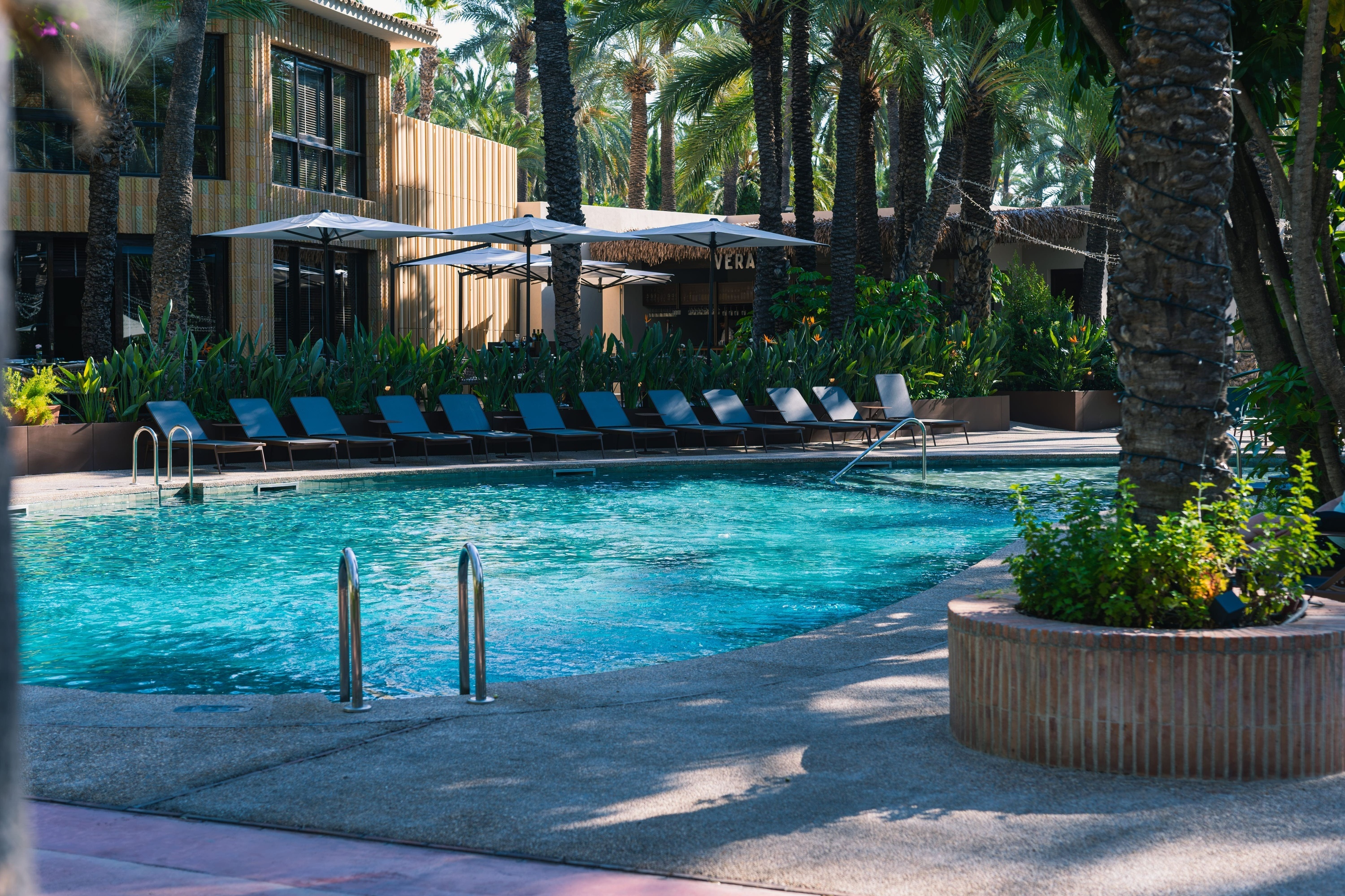 a large swimming pool surrounded by chairs and umbrellas