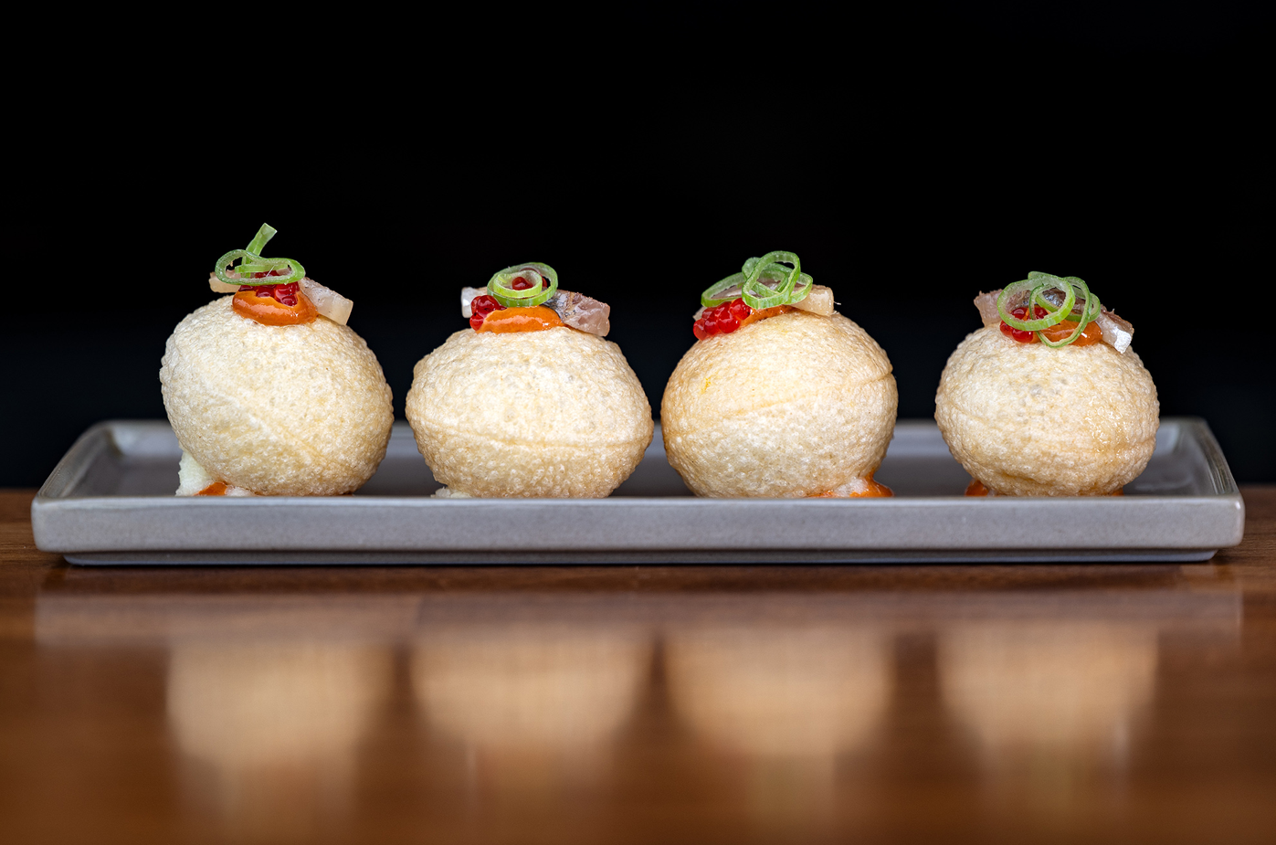 tres bolas de comida están en un plato sobre una mesa de madera
