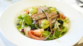 a salad with anchovies olives and tomatoes on a white plate