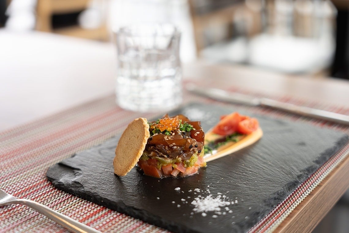 a plate of food on a table with a glass of water in the background