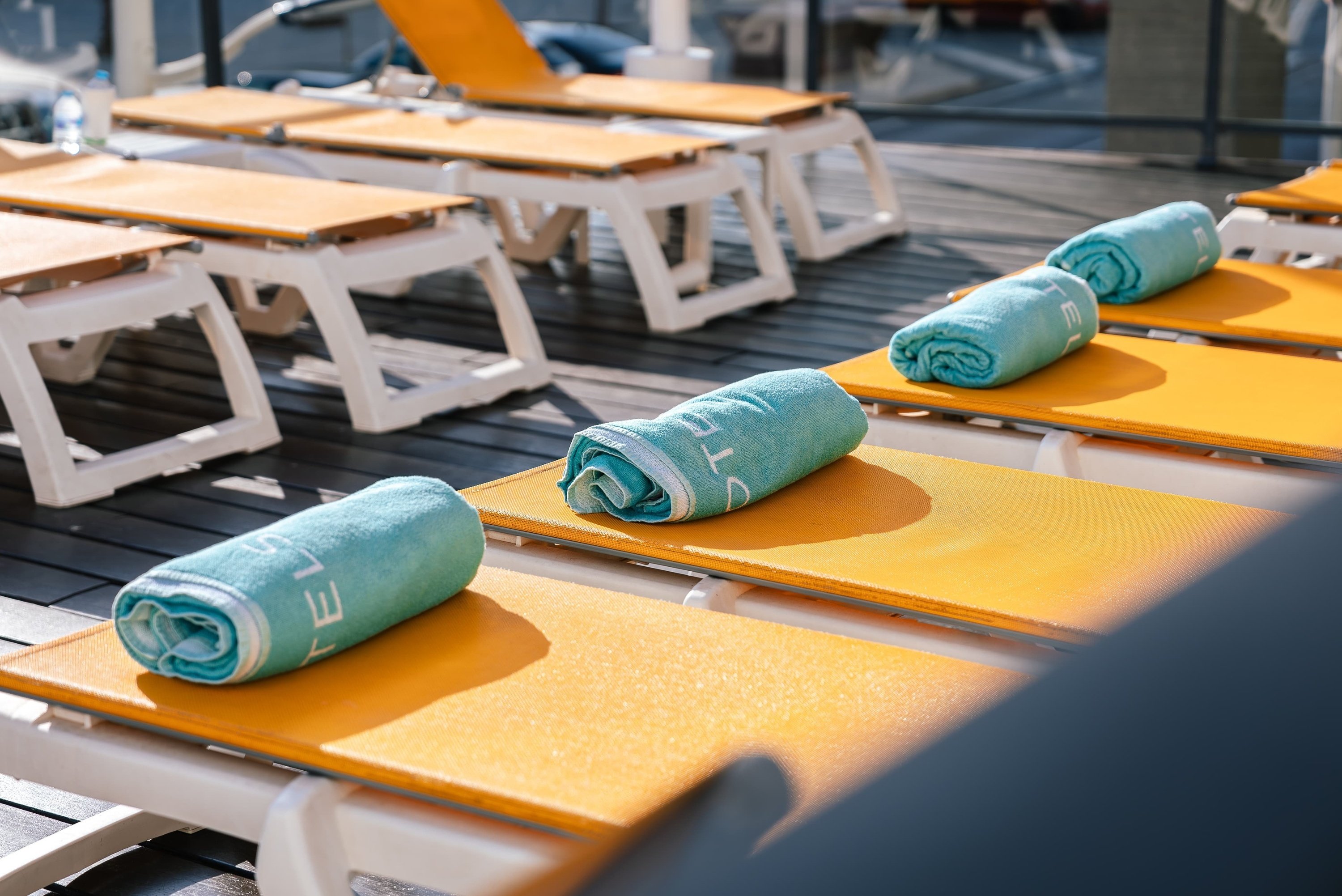 a blue towel with the letter e on it sits on a yellow lounge chair