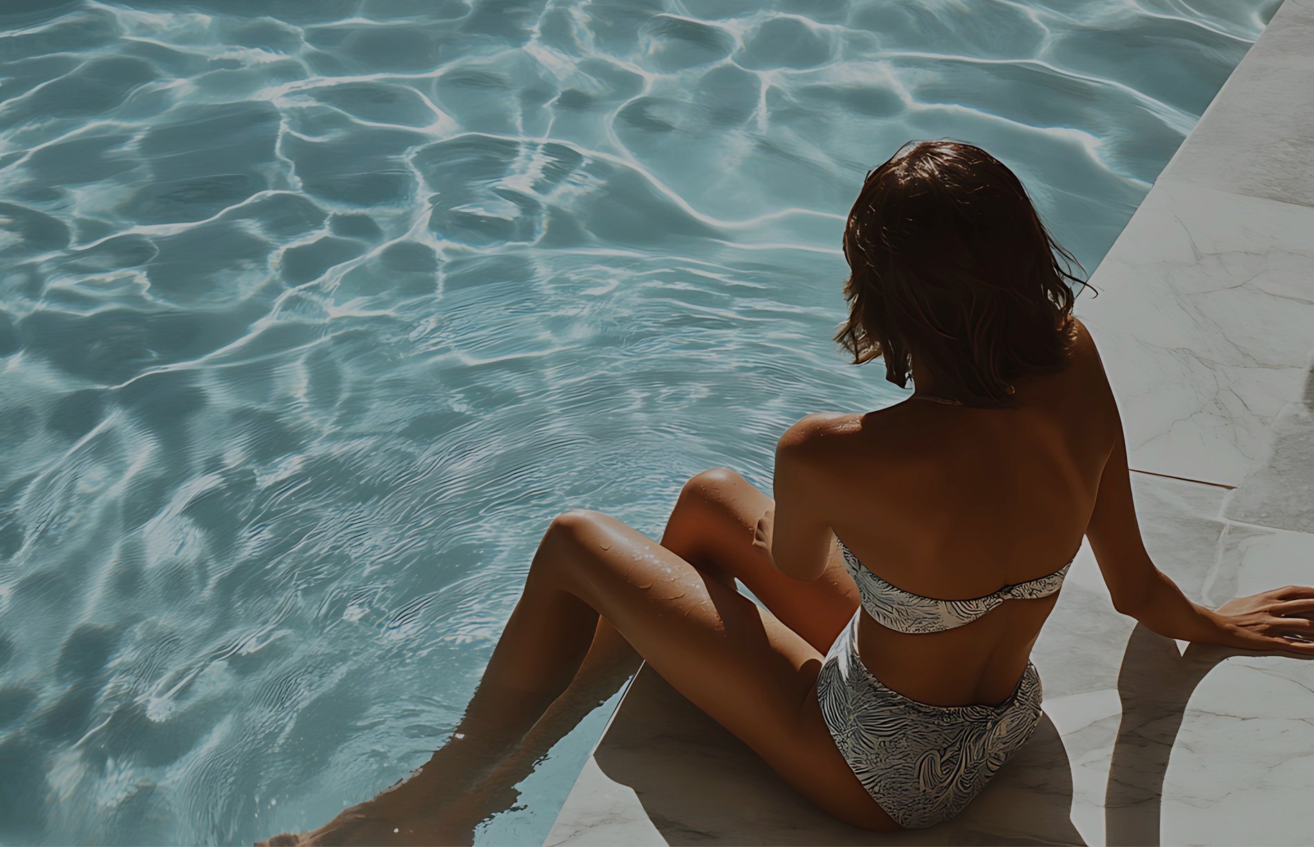 a woman in a bikini sits on the edge of a swimming pool