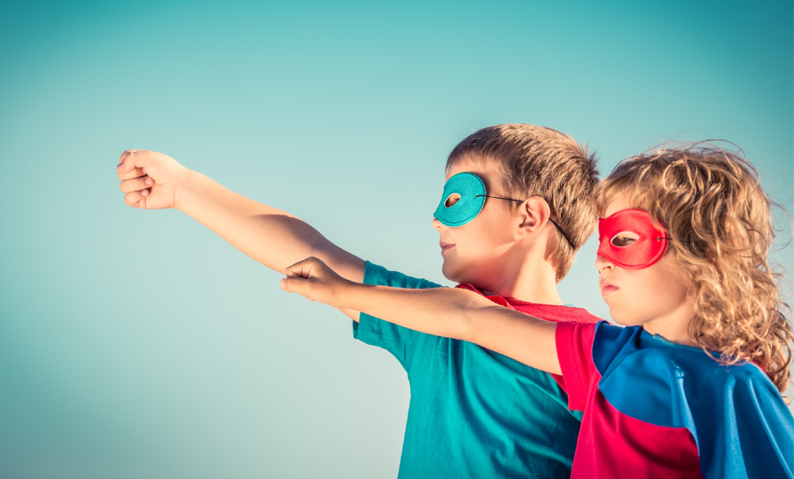 un niño y una niña con máscaras y capas de superhéroes miran hacia el cielo