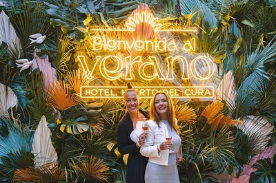 two women standing in front of a sign that says bienvenido al verano - 
