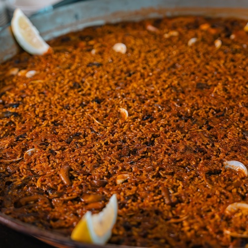 una sartén llena de arroz y camarones con rodajas de limón