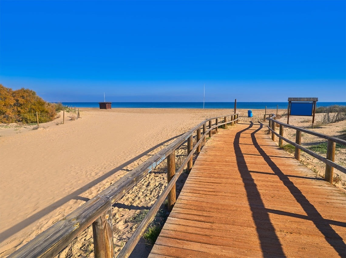 a wooden walkway leading to a beach with a sign that says 