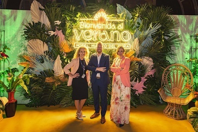 three people stand in front of a sign that says bienvenido al verano - 