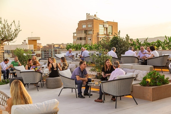 un grupo de personas están sentadas en sillas y mesas en un patio al aire libre