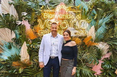 a man and woman pose in front of a sign that says bienvenido al verano - 