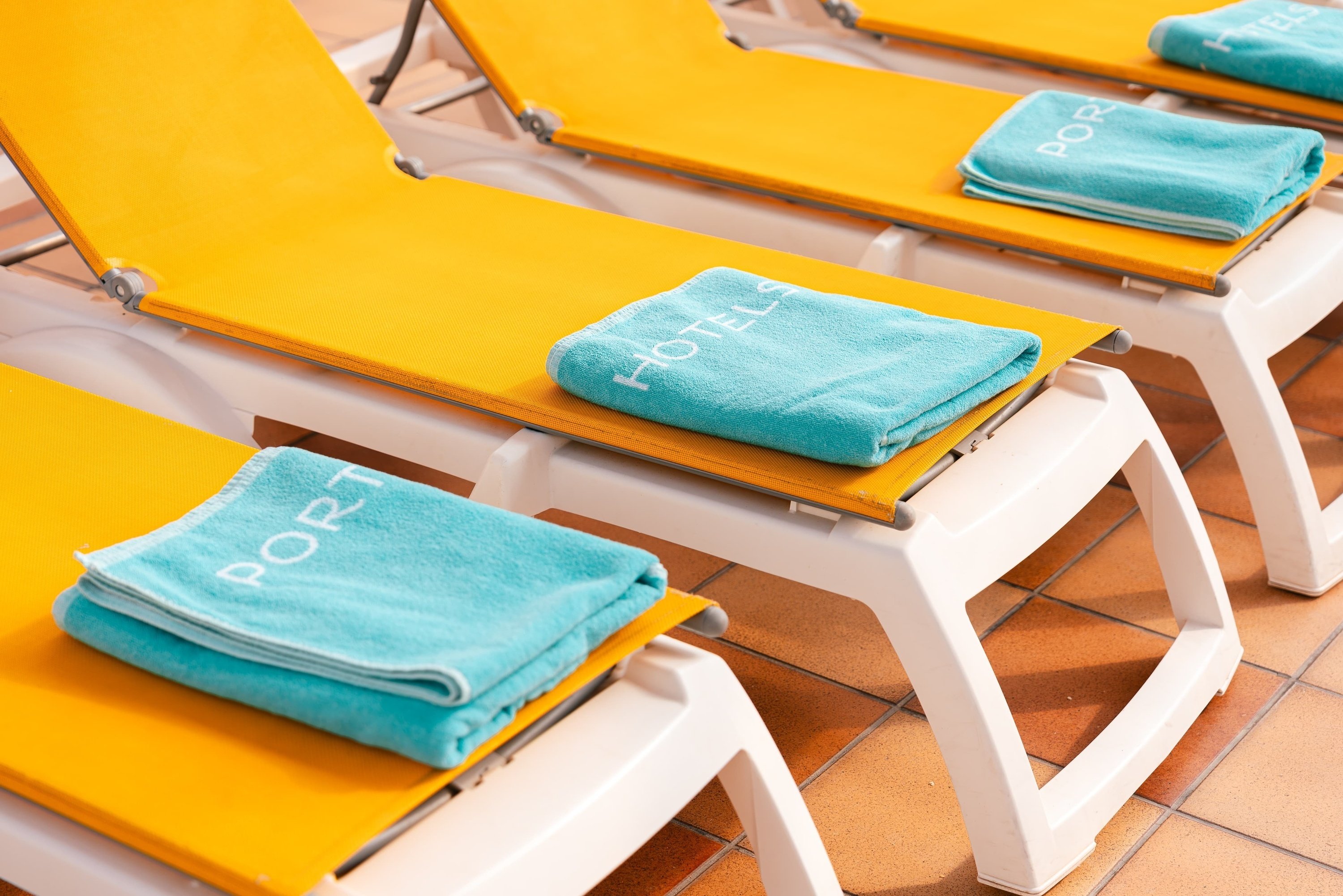 a yellow lounge chair with a blue towel that says port on it