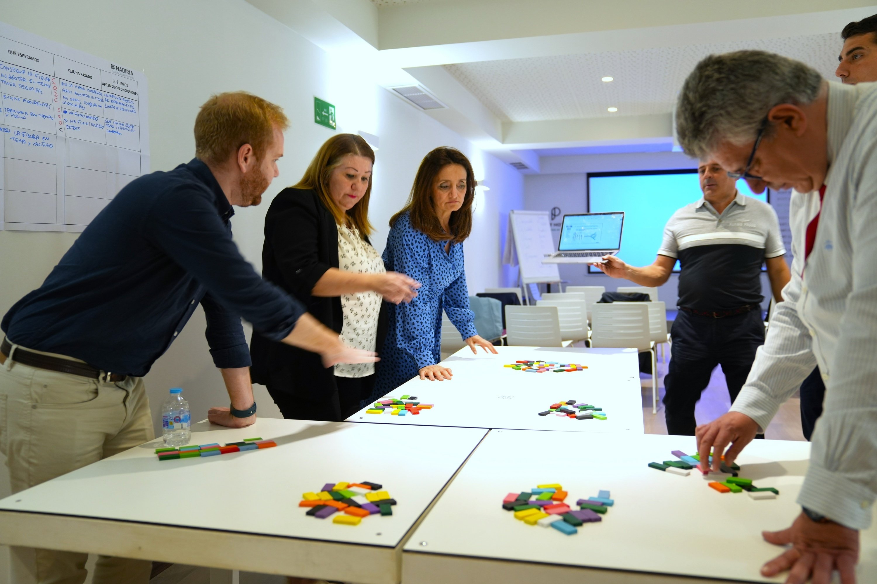 un grupo de hombres y mujeres están mirando una mesa llena de piezas de lego