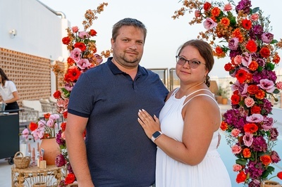 a man and a woman standing in front of a floral arch - 