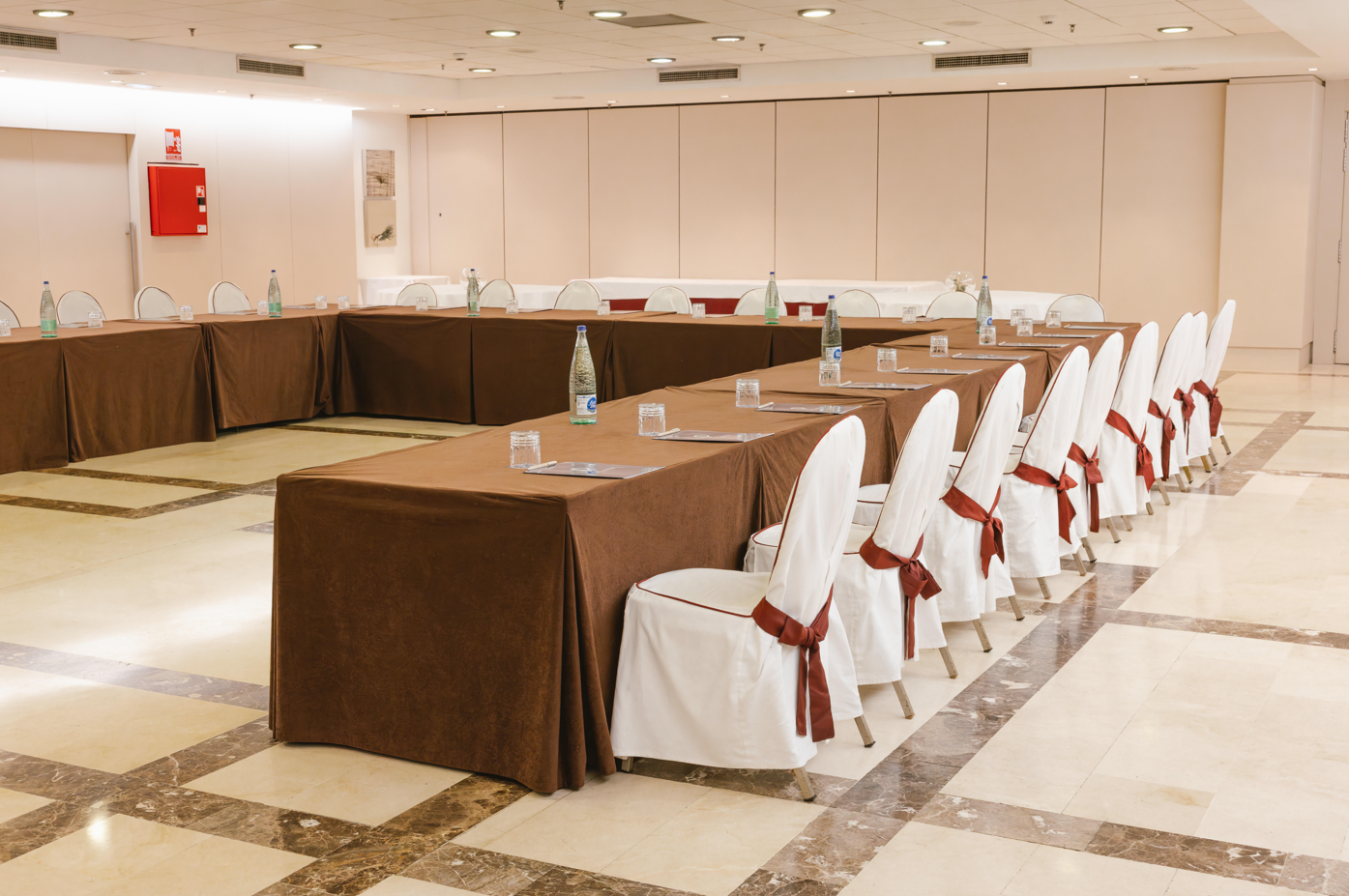 una sala de conferencias con mesas y sillas y una pantalla