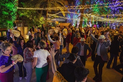 a crowd of people are dancing under a string of lights - 