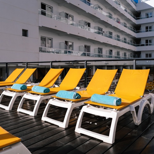 a row of yellow lounge chairs with blue towels on them