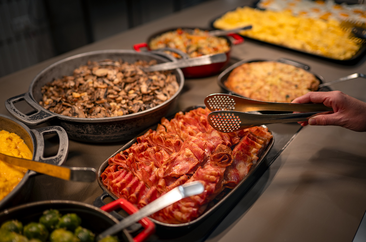 a person is using tongs to pick up bacon from a tray