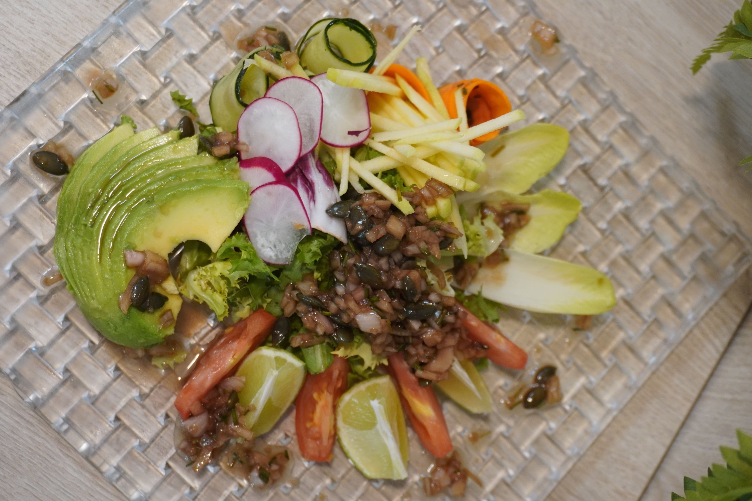 a salad with avocado radishes and tomatoes on a glass plate