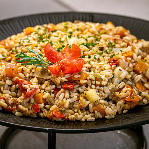 Ensalada de pasta con tomates y hierbas frescas, servida en plato negro. Port Hotels: Corporativa