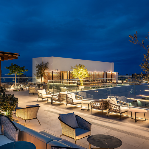 una terraza con muebles y una piscina al fondo