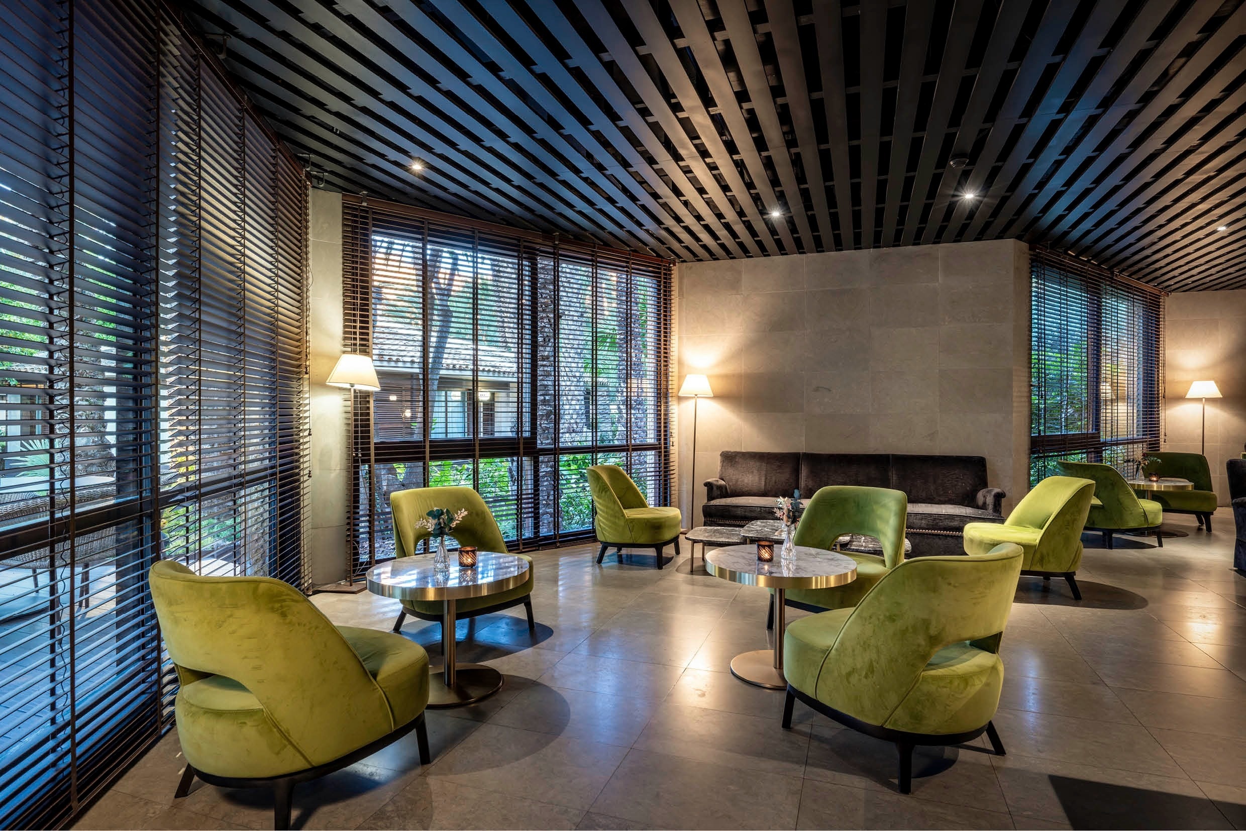 a room with green chairs and tables with candles on them