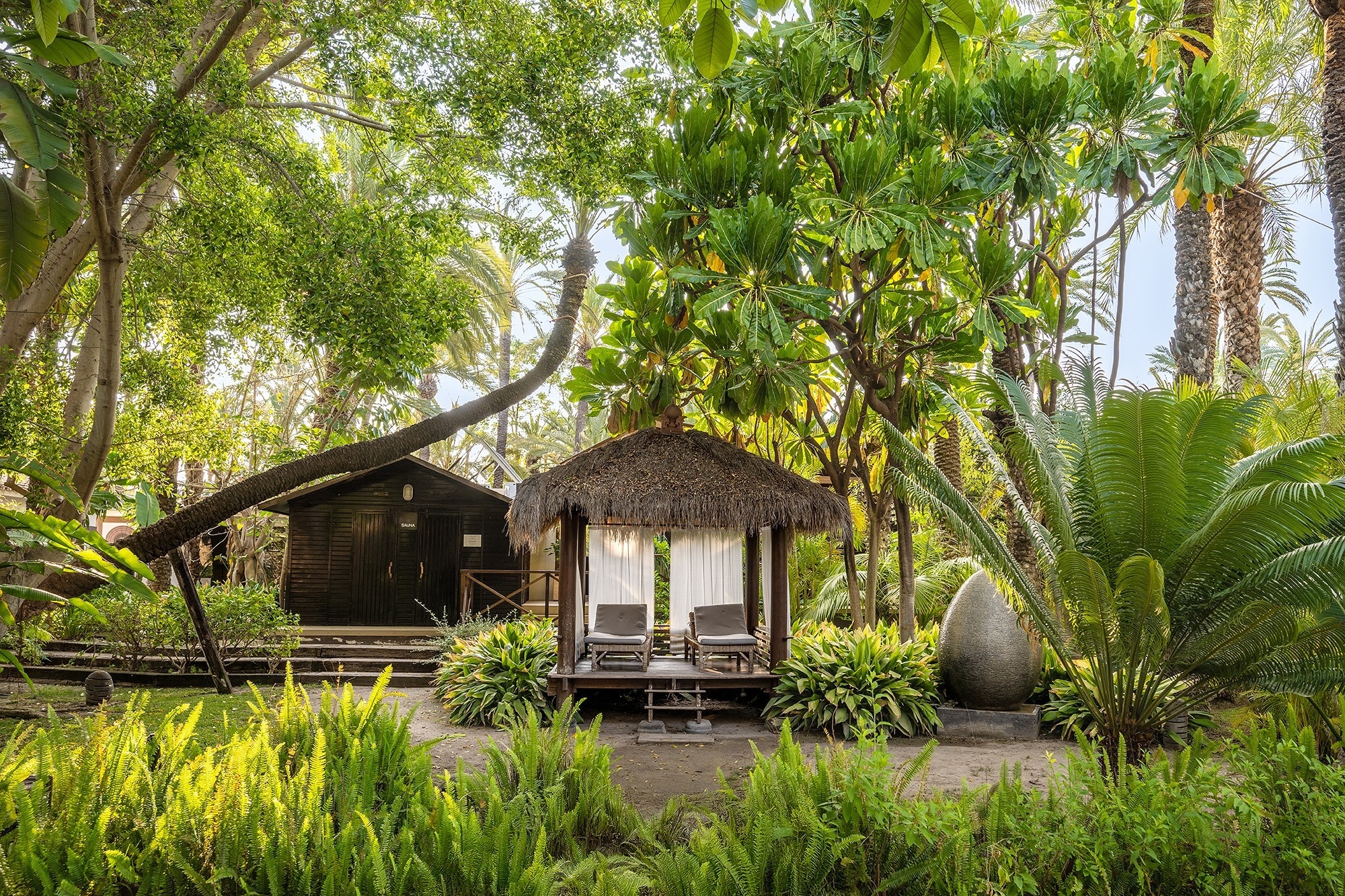 a hot tub is surrounded by lounge chairs under a wooden roof