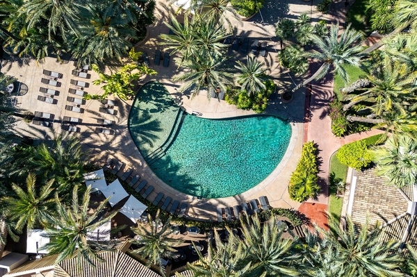 Piscina cristalina com palmeiras e espreguiçadeiras, ideal para relaxar nos Port Hotels: Corporativa.