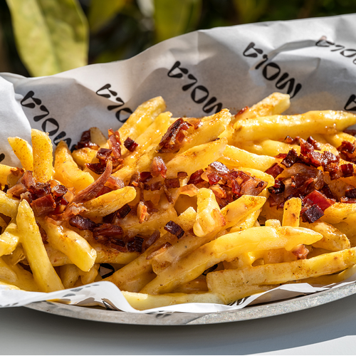 un plato de papas fritas con tocino y queso está envuelto en papel mola