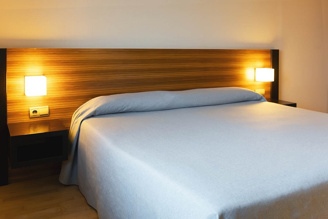 una cama con una colcha azul y una cabecera de madera