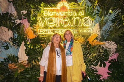 two women pose in front of a sign that says bienvenido al verano - 