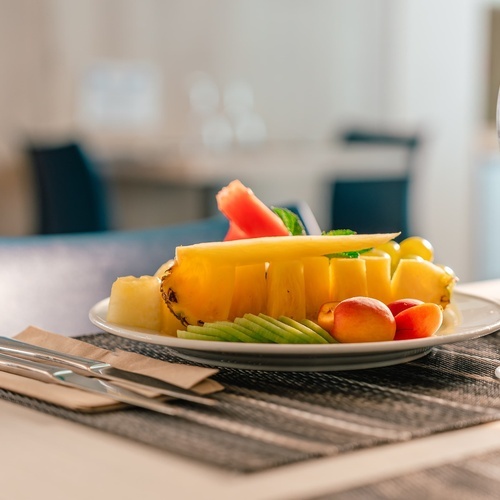 a plate of fruit sits on a table next to a glass of water