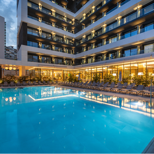 una gran piscina rodeada de sillas y balcones en un hotel