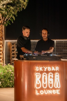 dos hombres tocan música frente a un letrero que dice skybar boga lounge - 