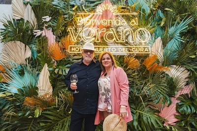 a man and woman standing in front of a sign that says bienvenida al verano - 