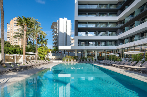 una piscina rodeada de sillas y sombrillas en un hotel