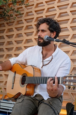 un hombre con barba toca una guitarra frente a un micrófono - 