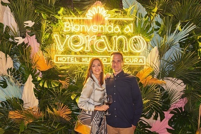 a man and woman standing in front of a sign that says bienvenido al verano - 