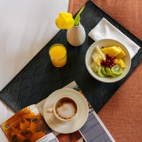 a tray with a bowl of fruit and a cup of coffee