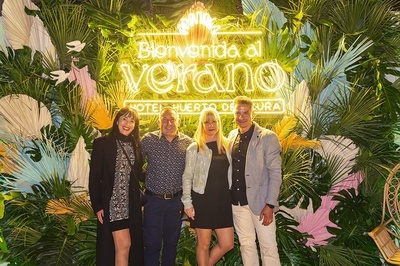 a group of people standing in front of a sign that says bienvenido al verano - 