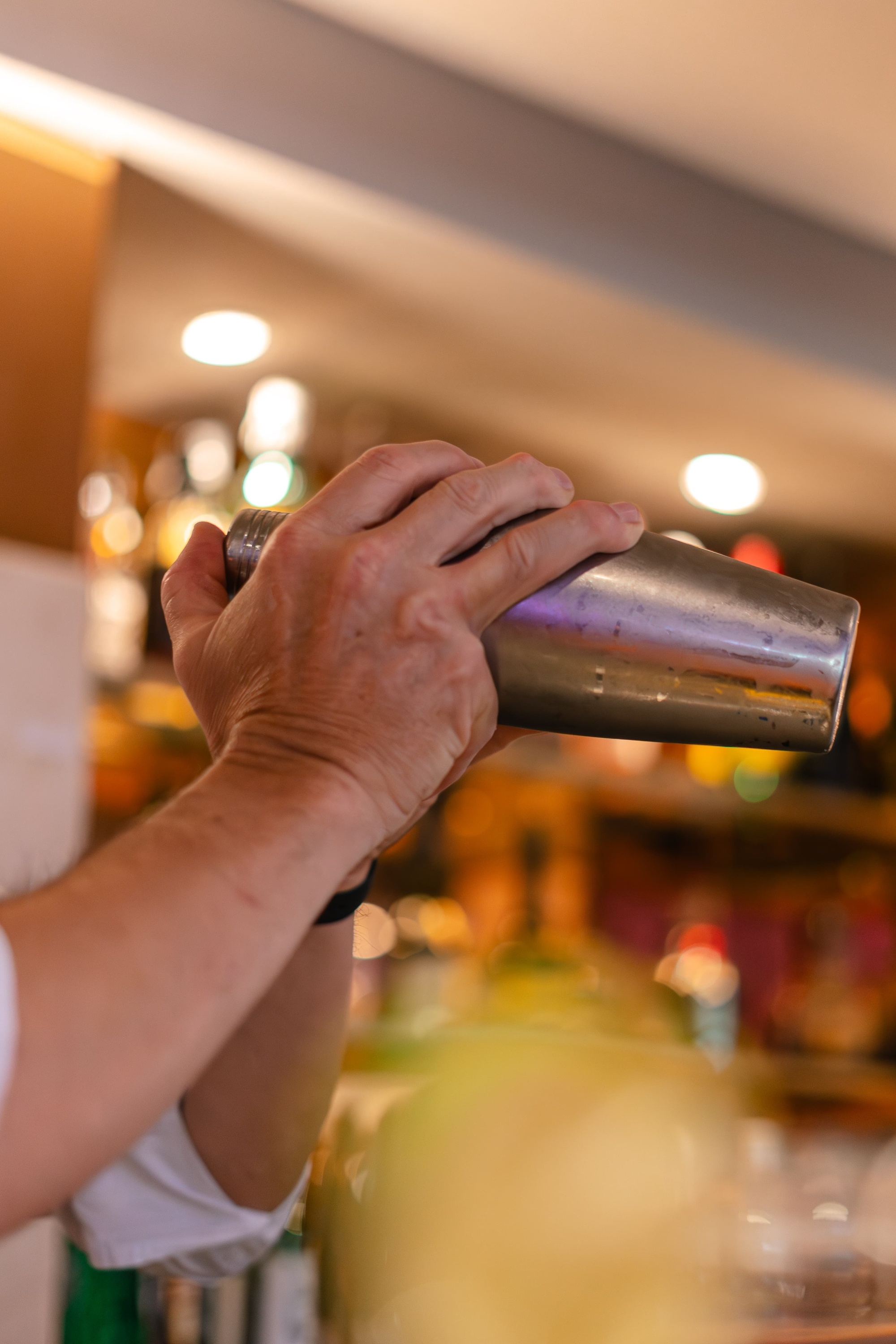 un barman agita un cóctel en un shaker de acero inoxidable