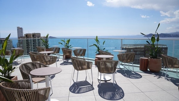 tables and chairs on a balcony overlooking the ocean